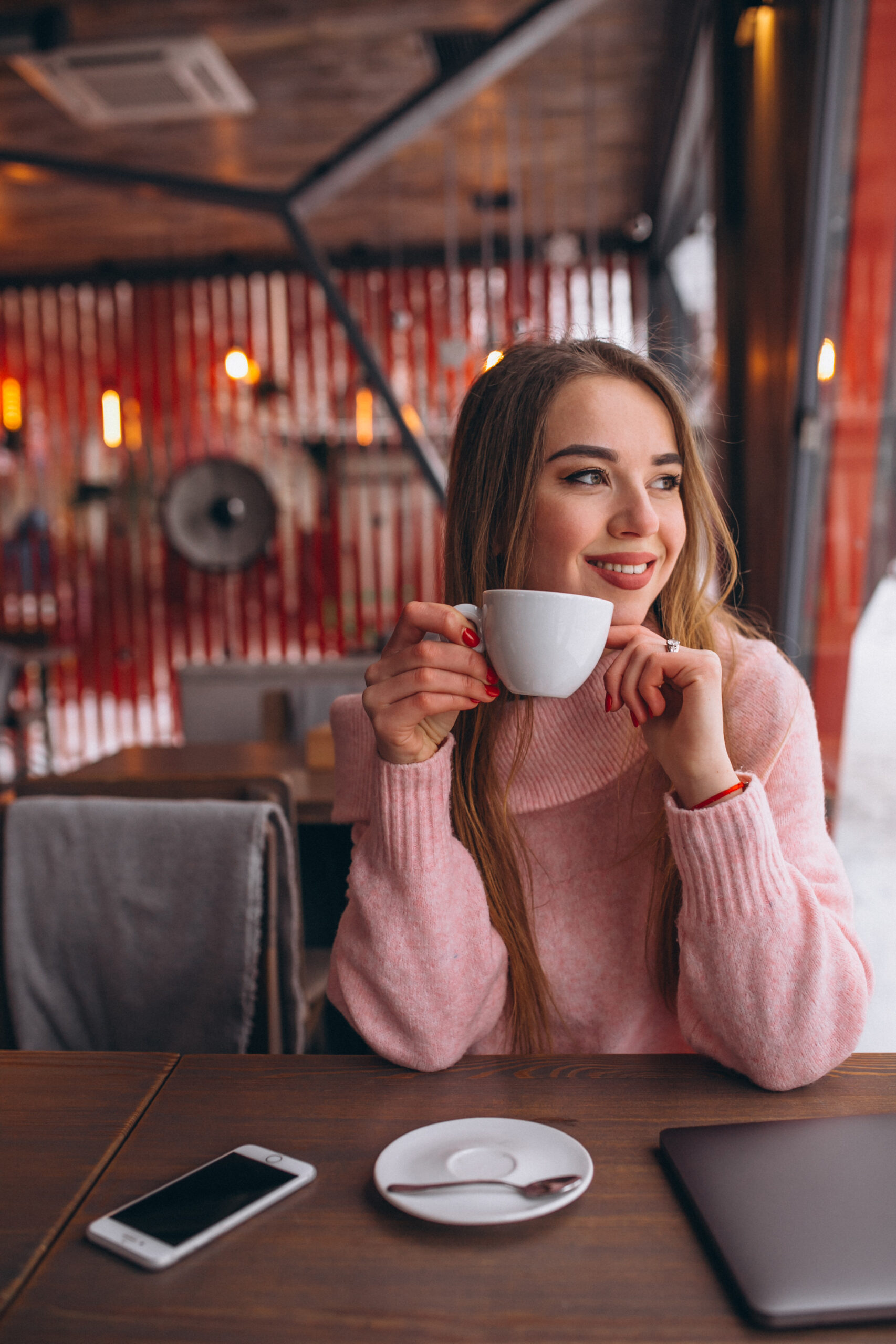 Woman in cafe drinking coffee and working on a computer