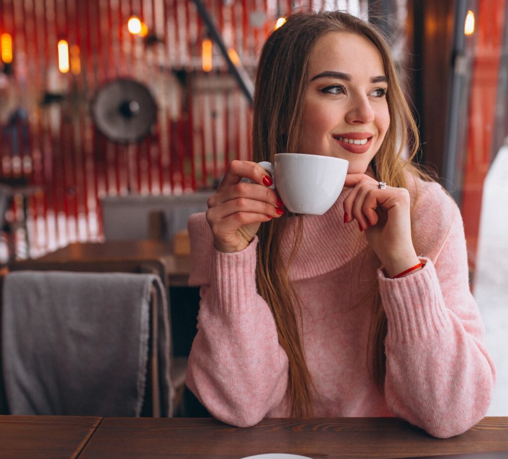 Woman in cafe drinking coffee and working on a computer